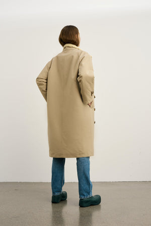 Dame i en stilren beige frakk fra MEOTINE, perfekt for enhver anledning. Kvalitet og design i fokus.