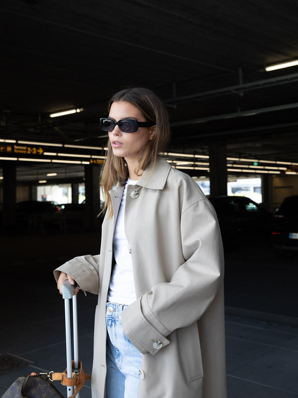 Dame med solbriller står ved en koffert, iført en stilren MEOTINE skinnjakke.