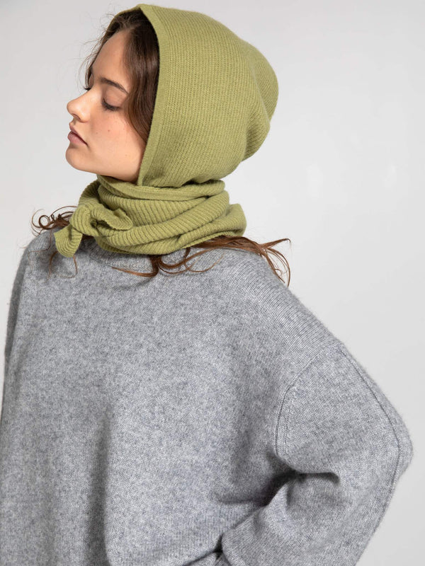 Dame i en stilren grå genser med grønn lue, perfekt for høsten. Oppdag MEOTINEs unike lærjakker.