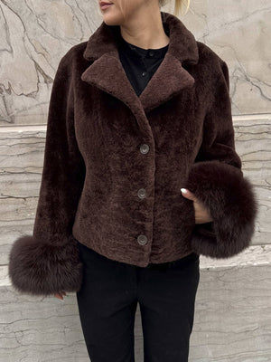 Dame i en stilren jakke fra MEOTINE, med myke pelsdetaljer og en elegant brun farge. Perfekt for høsten.