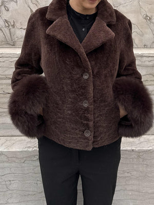 Dame i en stilren jakke fra MEOTINE, med myke pelsdetaljer og en elegant brun farge. Perfekt for høsten.