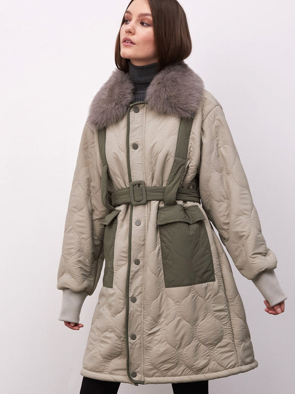 Dame i en stilren jakke fra MEOTINE, med pelskrage og belte for en moderne look. Perfekt for kalde dager.
