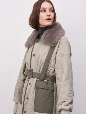 Dame i en stilren jakke fra MEOTINE, med pelskrage og belte for en moderne look. Perfekt for høst.
