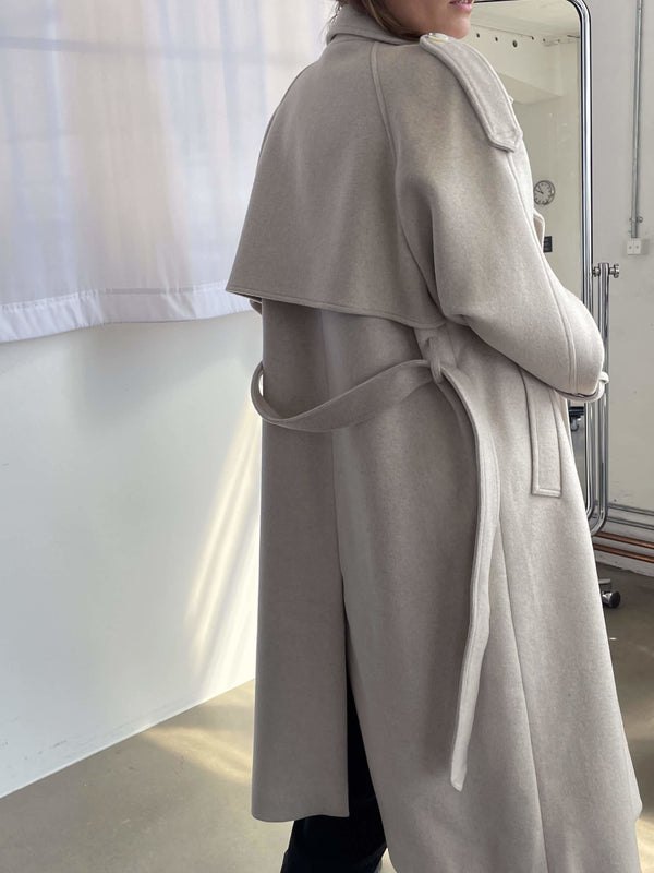 Dame i en stilren kåpe fra MEOTINE, perfekt for enhver anledning med elegant belte og moderne design.